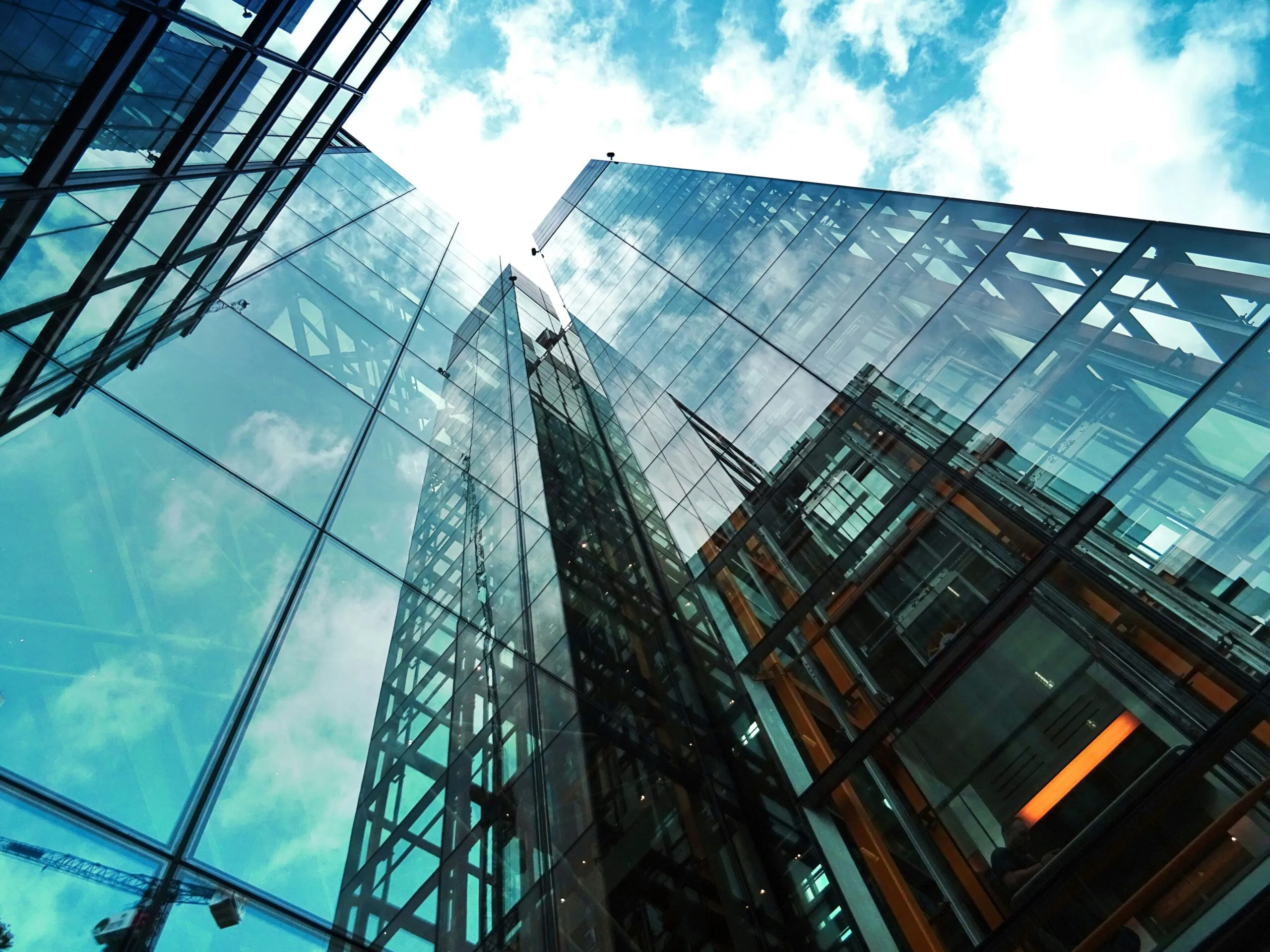 Glass office towers seen from street level against a blue sky